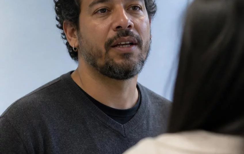 Duas pessoas frente a frente na mesa: uma sustenta a fala, a outra anota o que ouviu
